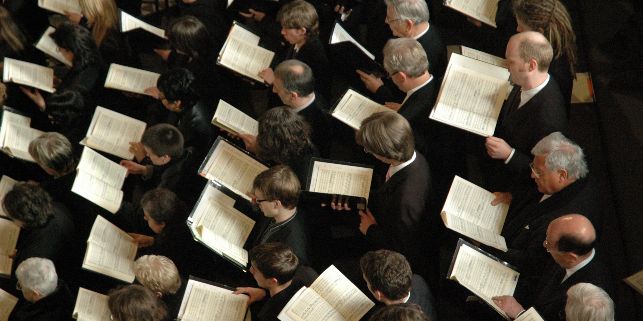 Domchor Sängerinnen und Sänger halten ihr Notenheft vor sich
